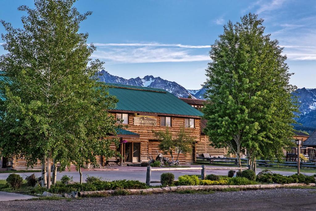 a log cabin with trees and mountains in the background at Stanley High Country Inn in Stanley