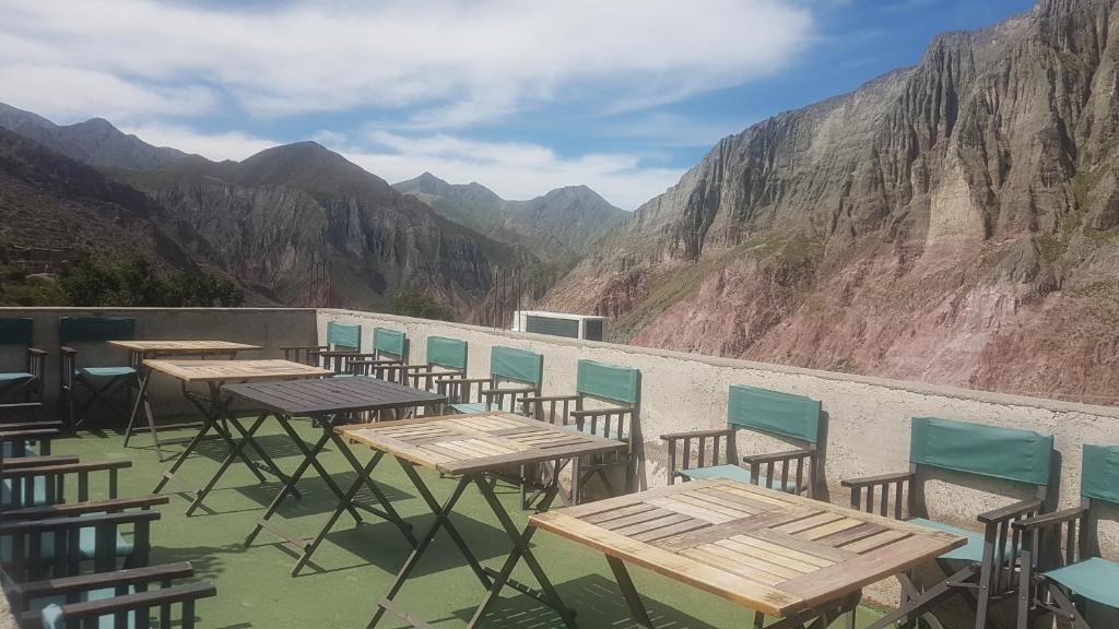 a row of tables and chairs on a balcony with mountains at Hostal Tacacho in Iruya