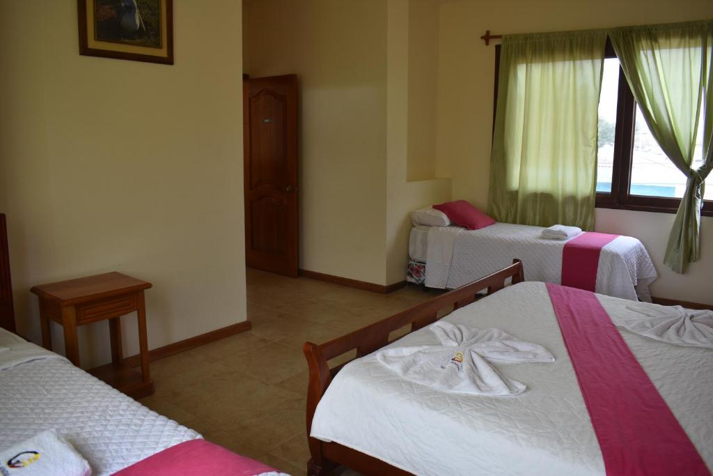 a hotel room with three beds and a window at Apartments Center GSV in Puerto Villamil