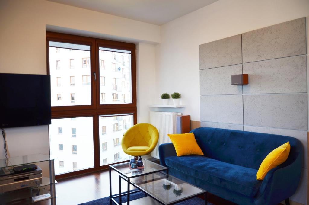a living room with a blue couch and a yellow chair at aleja Wyścigowa 4C by Homeprime in Warsaw