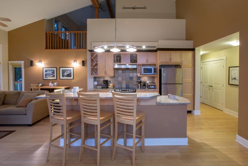 a kitchen and living room with a bar and chairs at Painted Boat Resort Spa and Marina in Madeira Park