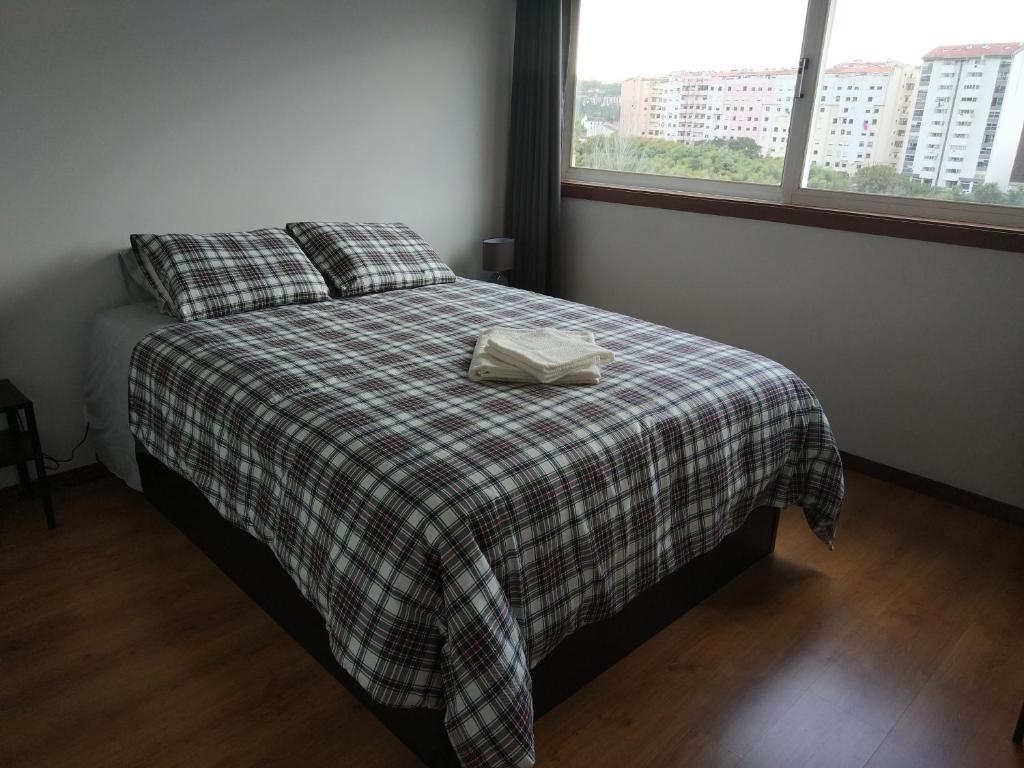 a bedroom with a bed with a plaid blanket and two windows at AL das Fonsecas in Coimbra