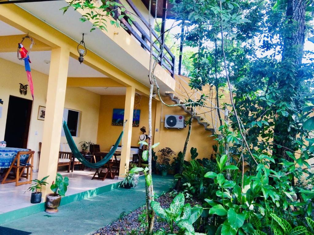 une maison avec une terrasse couverte dotée d'un hamac. dans l'établissement Pousada Flor de Gaia, à Guarujá