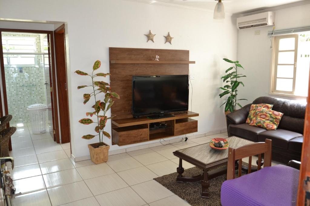 sala de estar con TV, sofá y mesa en jardim das toninhas, en Ubatuba