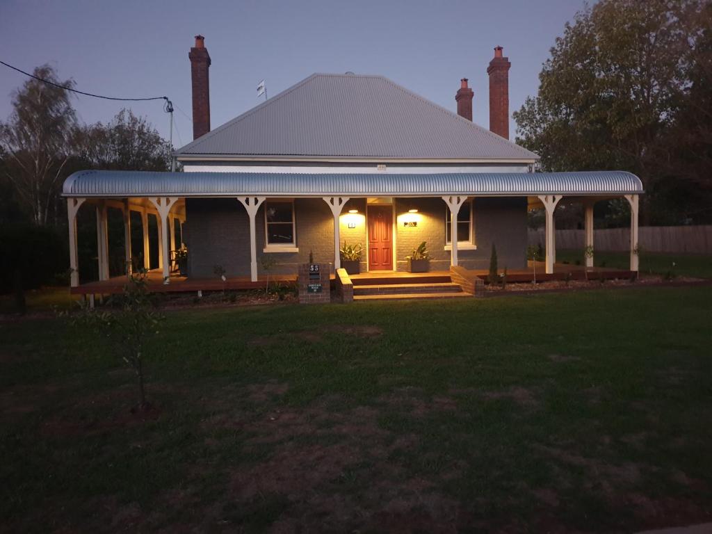 a white house with a porch and a yard at Kings Cottage Uralla in Uralla