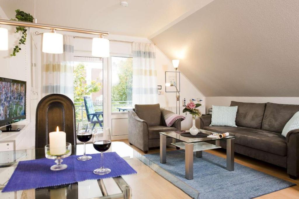 uma sala de estar com um sofá e uma mesa com copos de vinho em Deich-Residenz App. 6 em Grömitz