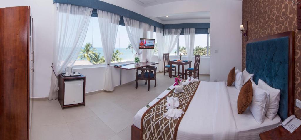 a hotel room with a bed and a table and chairs at Mount Breeze Hotel in Mount Lavinia