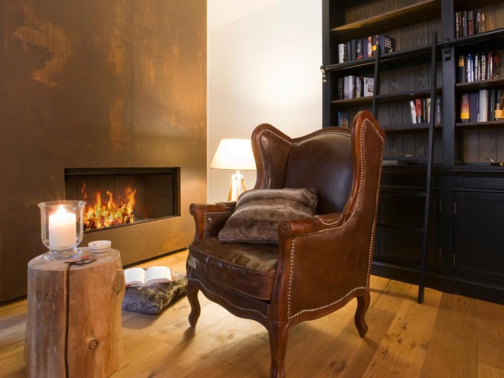 una silla de cuero en una sala de estar con chimenea en AR Mountains Lodge Villachiara en Branzi