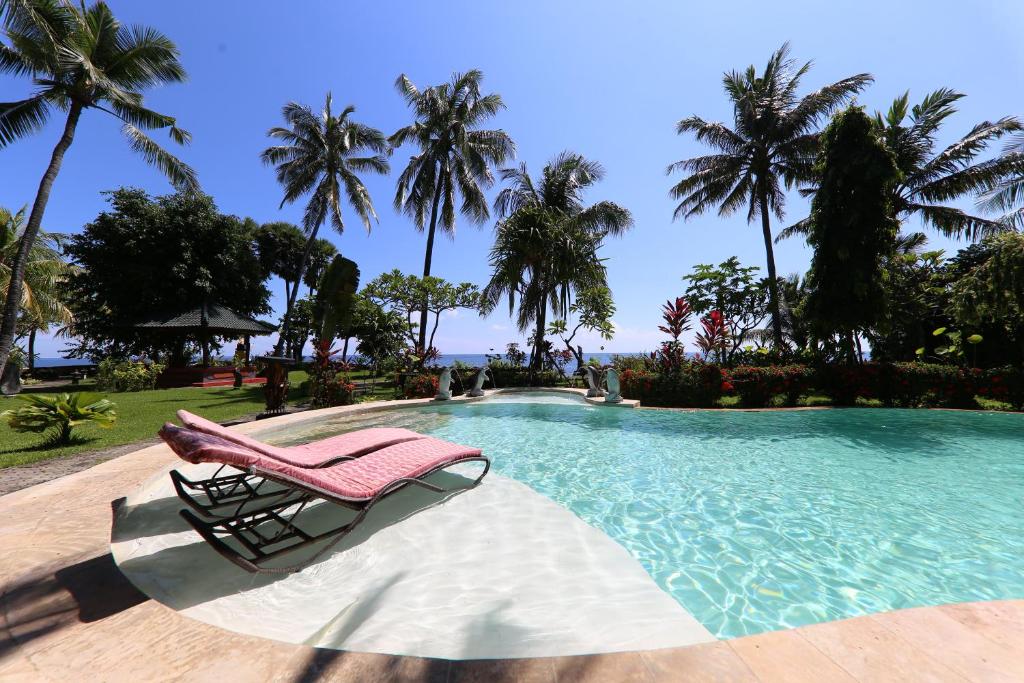 una silla junto a una piscina con palmeras en Felicianas Resort, en Tejakula
