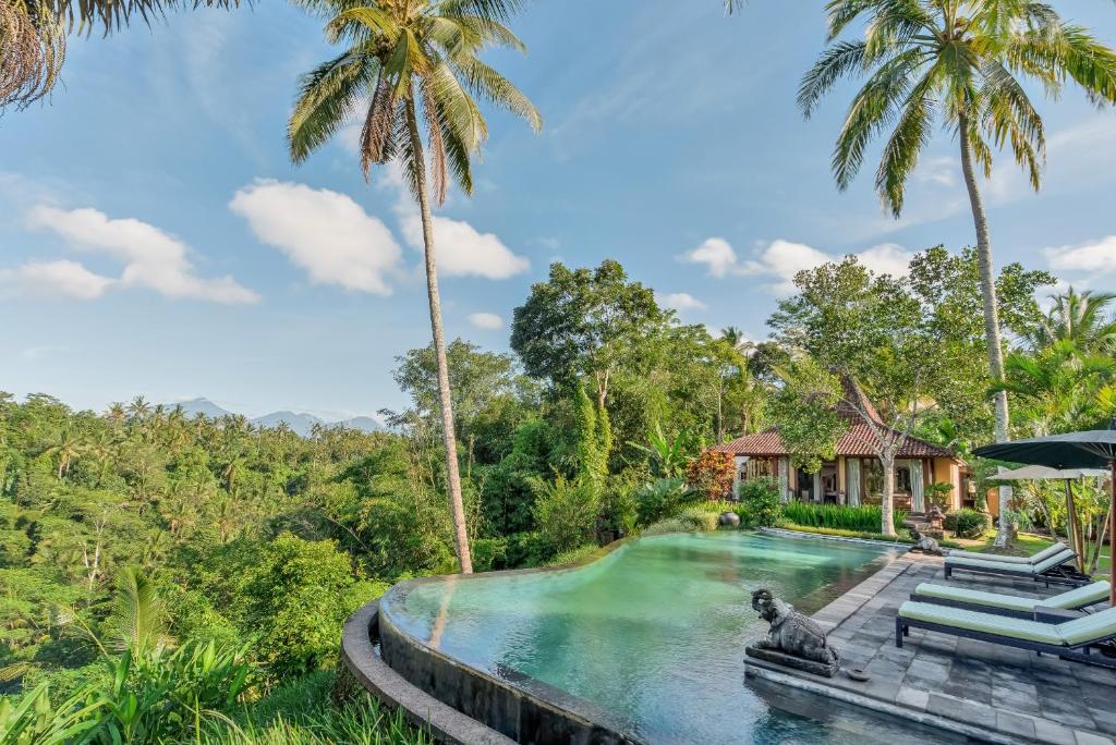 a pool at a resort with palm trees at Villa Bodhi in Payangan