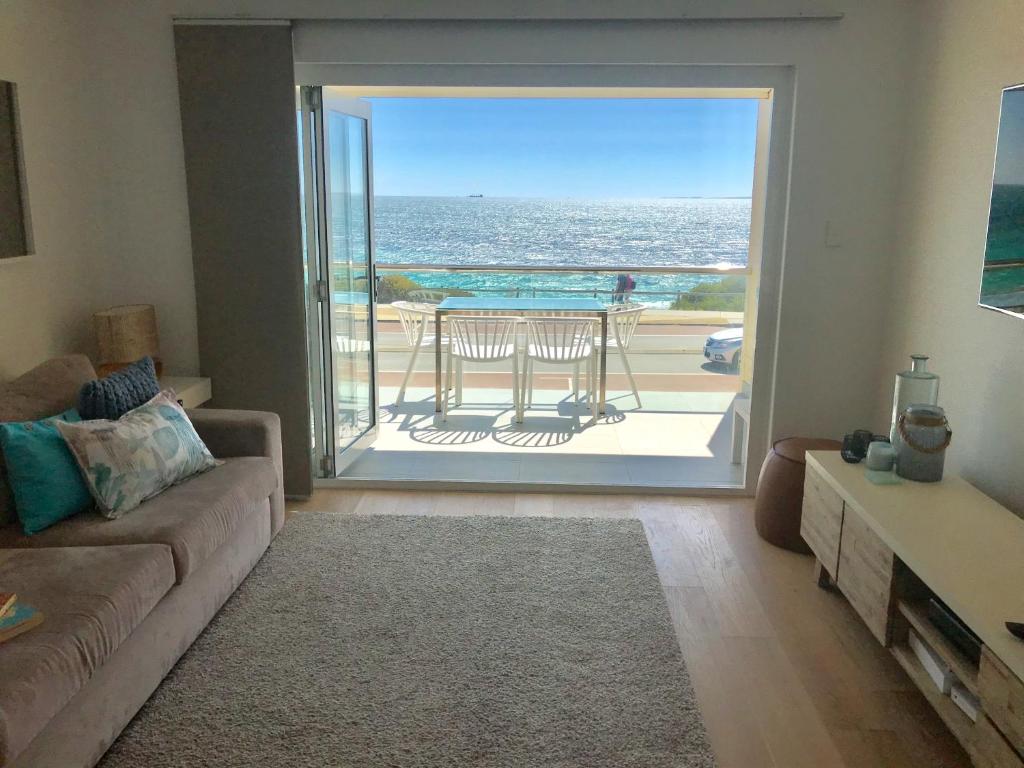 a living room with a couch and a view of the ocean at Cottesloe Beachfront Ocean View Apartment in Perth