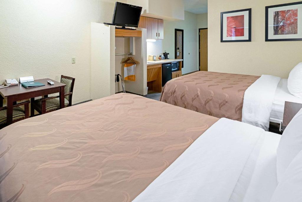 a hotel room with two beds and a desk at Quality Inn & Suites in Robbinsville