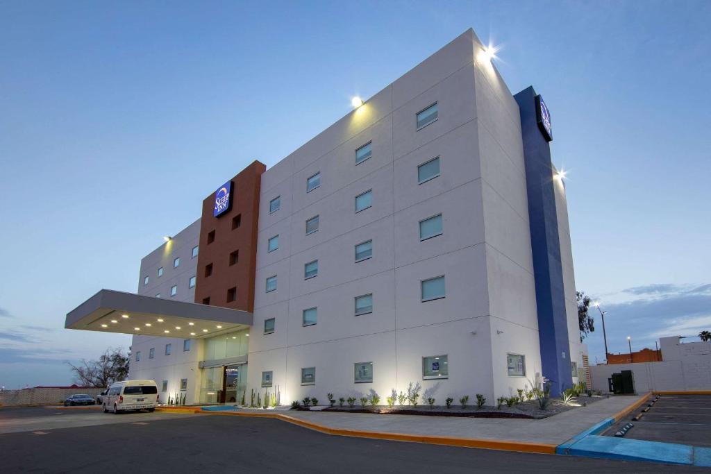 a hotel building with a van parked in front of it at Sleep Inn Mexicali in Mexicali