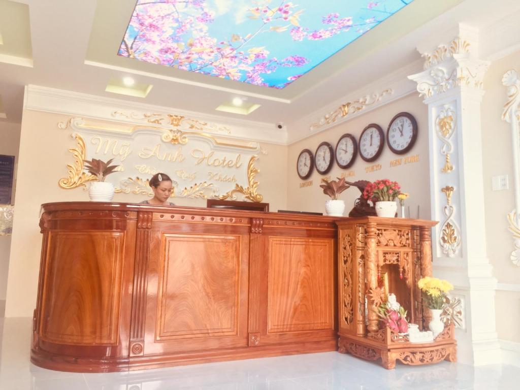 una mujer de pie detrás de un mostrador en una habitación con un tragaluz en Hotel Mỹ Anh, en Sa Ðéc