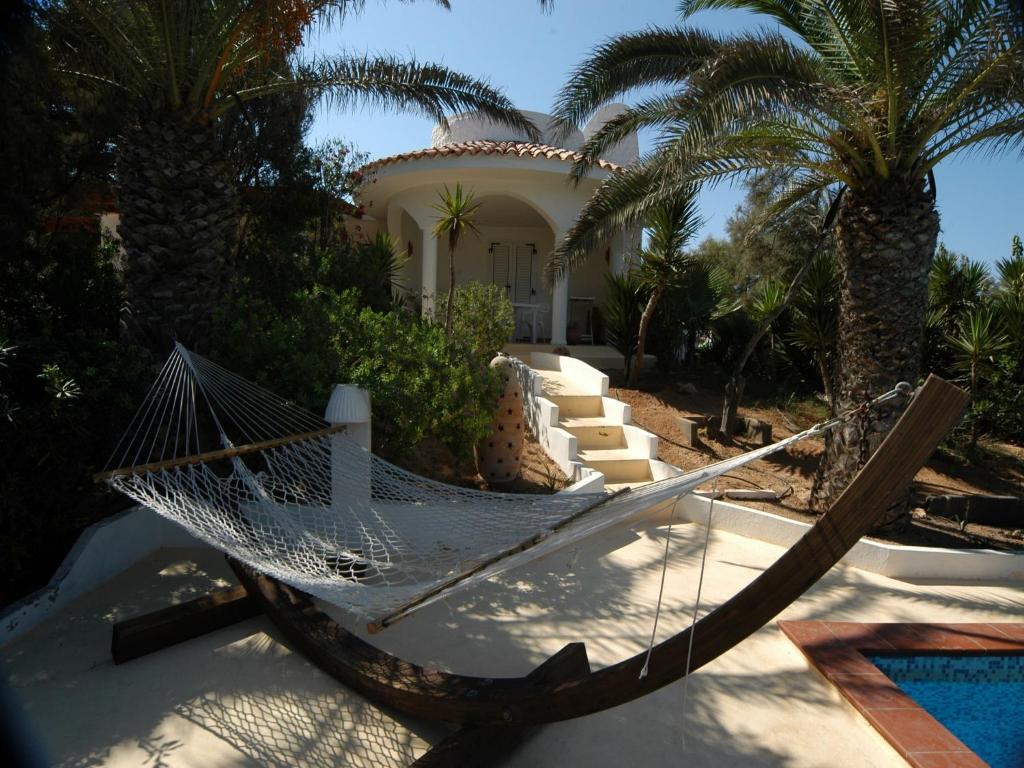 a hammock in front of a house with palm trees at Oasi Di Casablanca in Lampedusa