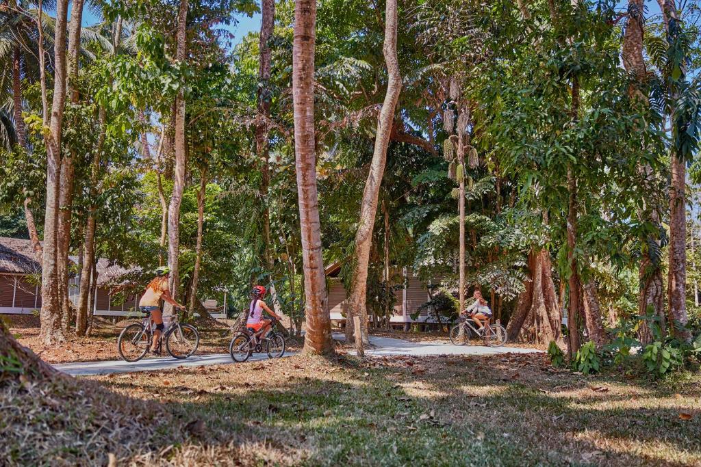 three people riding bikes down a path in a forest at Taj Exotica Resort & Spa, Andamans in Havelock Island