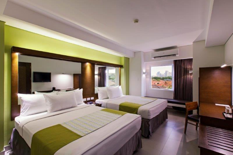 Habitación de hotel con 2 camas y escritorio en Microtel by Wyndham Acropolis, en Manila