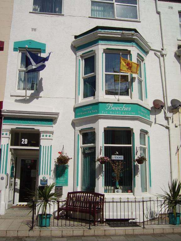ein weißes Gebäude mit zwei Bänken davor in der Unterkunft Beeches Hotel in Blackpool