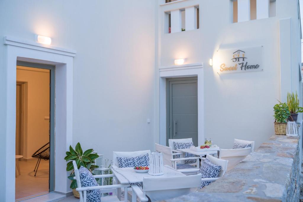 a patio with white chairs and tables and a building at Sweet Home Naxos in Naxos Chora