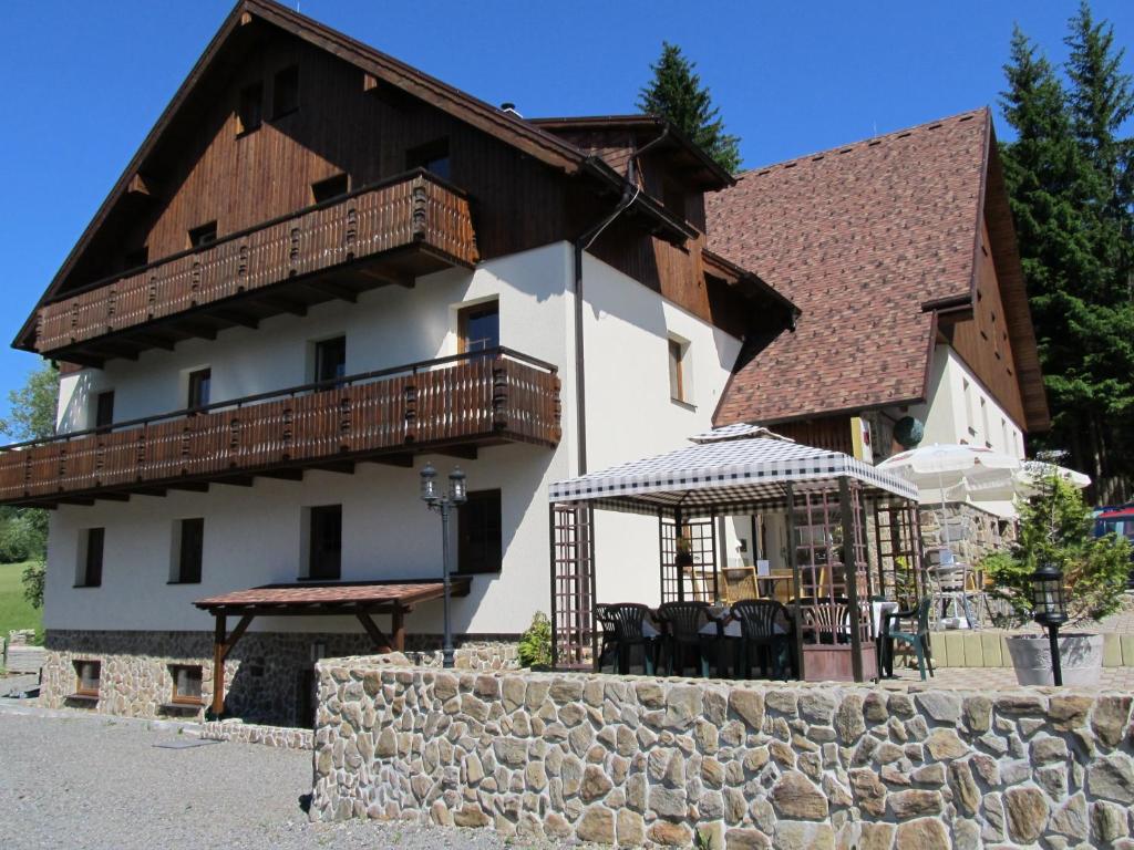 a large house with a balcony and a table and chairs at Apartmány Alpský Dům in Železná Ruda