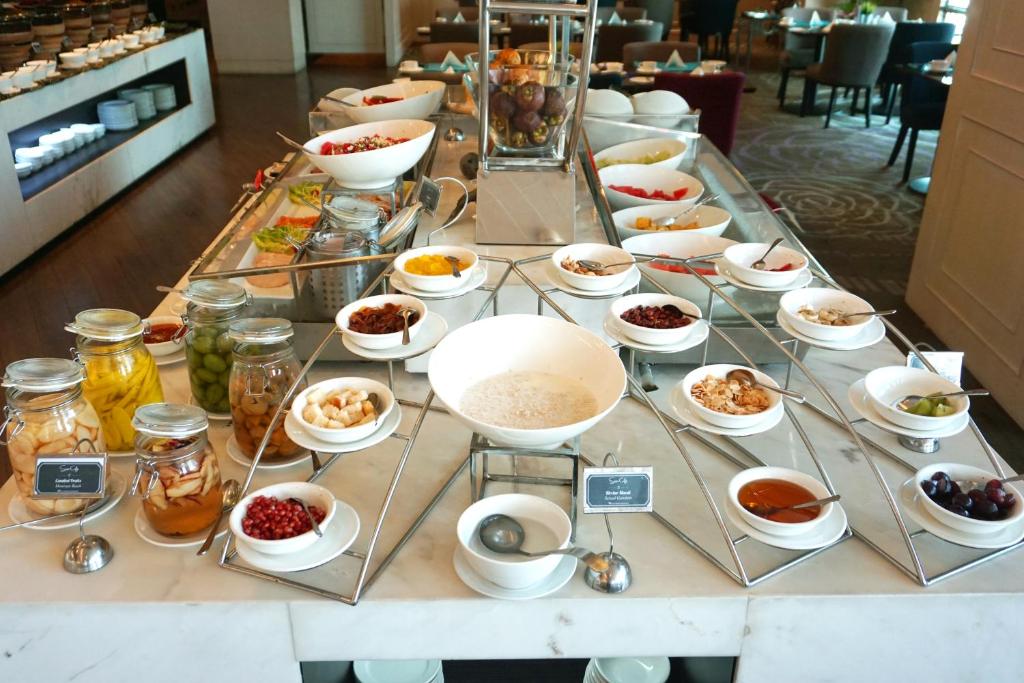a buffet line with bowls of food on a table at Swiss-Belhotel Airport Jakarta in Tangerang
