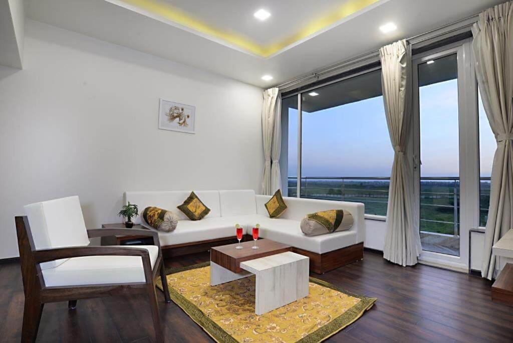a living room with a white couch and a large window at Comfort Inn Donil Vadodara in Vadodara