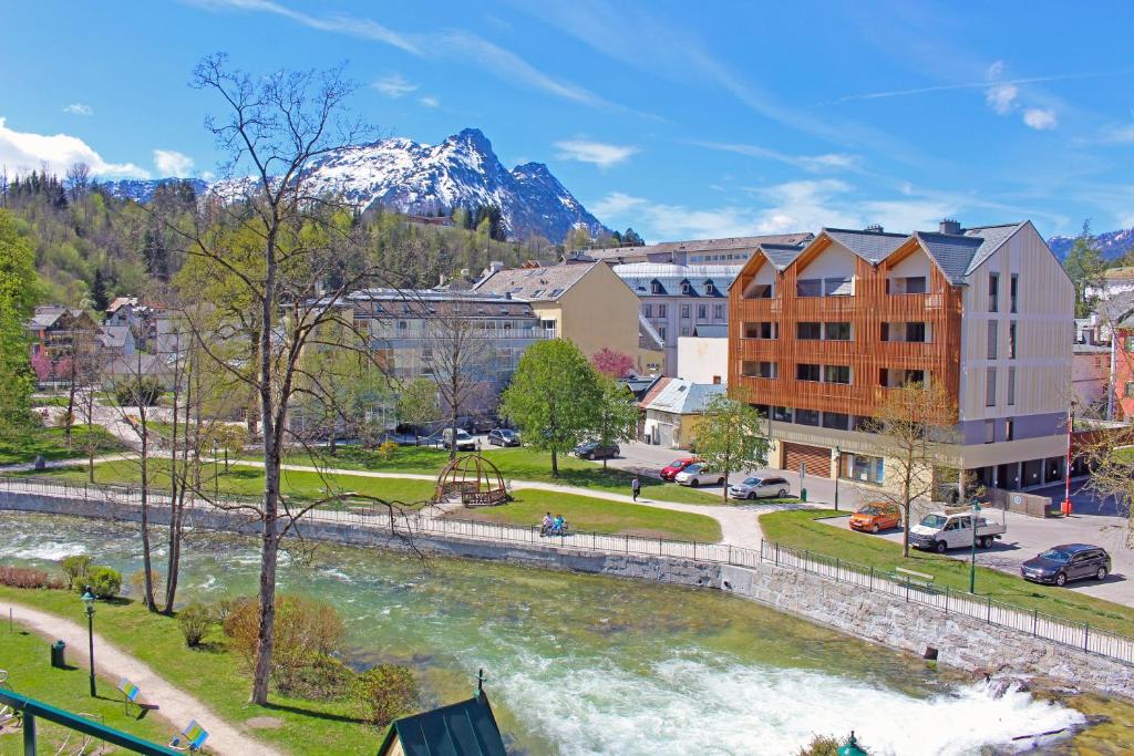 eine Stadt mit einem Fluss und Gebäuden und einem Berg in der Unterkunft Ferienwohnung Narzisse - City Appartement im Kurpark Bad Aussee in Bad Aussee