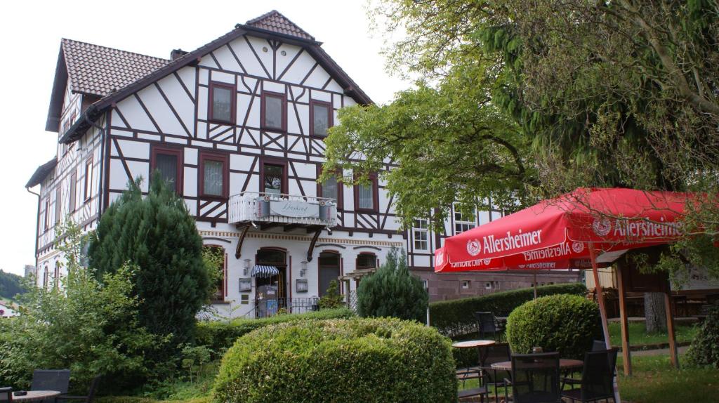 a white and black house with a red umbrella at LandHotel Lönskrug in Hellental