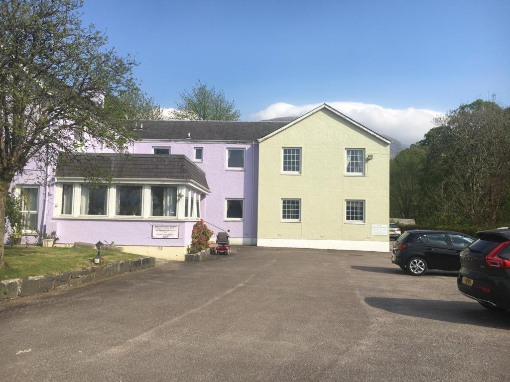 a house with a car parked in a parking lot at Glenlochy Nevis Bridge Apartments in Fort William