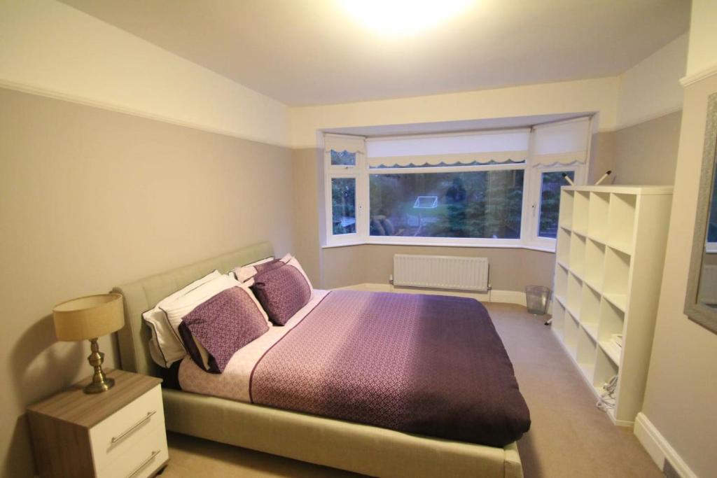 Oak Tree في لندن: غرفة نوم مع سرير مع وسائد أرجوانية ونافذة