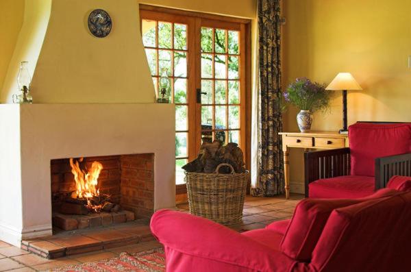 a living room with red chairs and a fireplace at Inversanda Farm Cottages in Dargle
