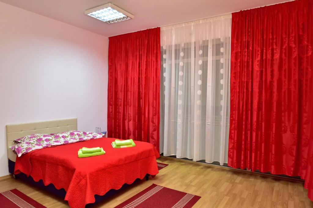 a bedroom with a red bed and red curtains at Pensiunea La Safari in Tîrgu Neamţ