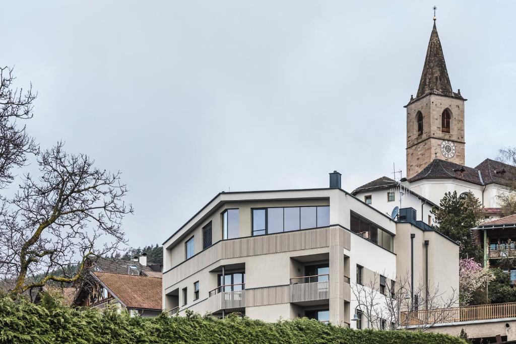 a building with a clock tower and a church at Luis & die Buabm - Gasthof Jenesien in San Genesio Atesino