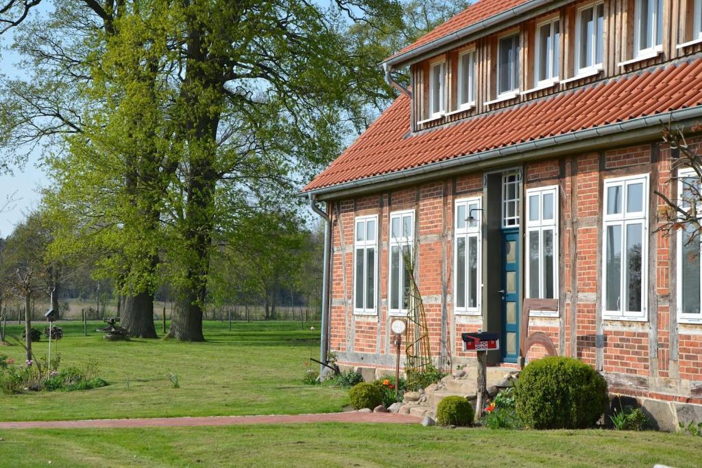 a brick house with a red roof and a yard at Ferienwohnung Heidjerleev in Eldingen