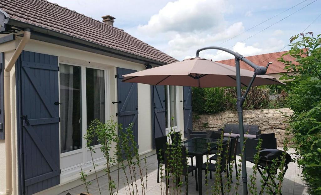 eine Terrasse mit einem Sonnenschirm, einem Tisch und Stühlen in der Unterkunft Au pied de l étang et du canal du Nivernais bazolles in Bazolles