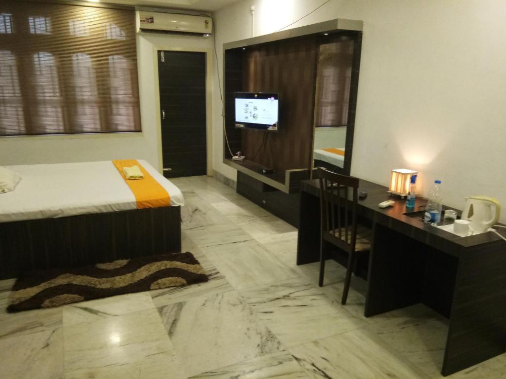 a hotel room with a bed and a desk and a television at Apurba's Pensione in Guwahati