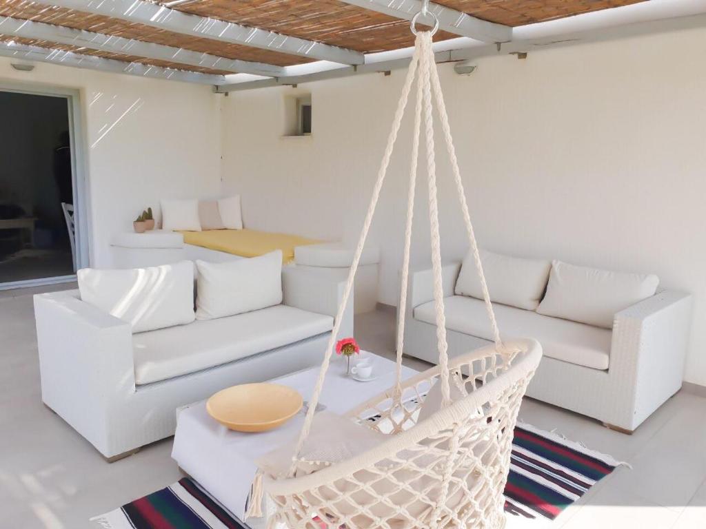 una sala de estar con muebles blancos y una hamaca. en Thomas Apartments in Katapola, en Amorgós