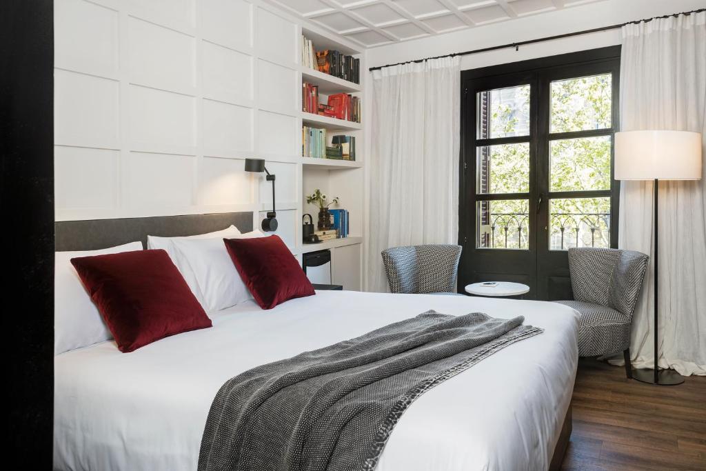 a bedroom with a large white bed with red pillows at Yurbban Ramblas Boutique Hotel in Barcelona