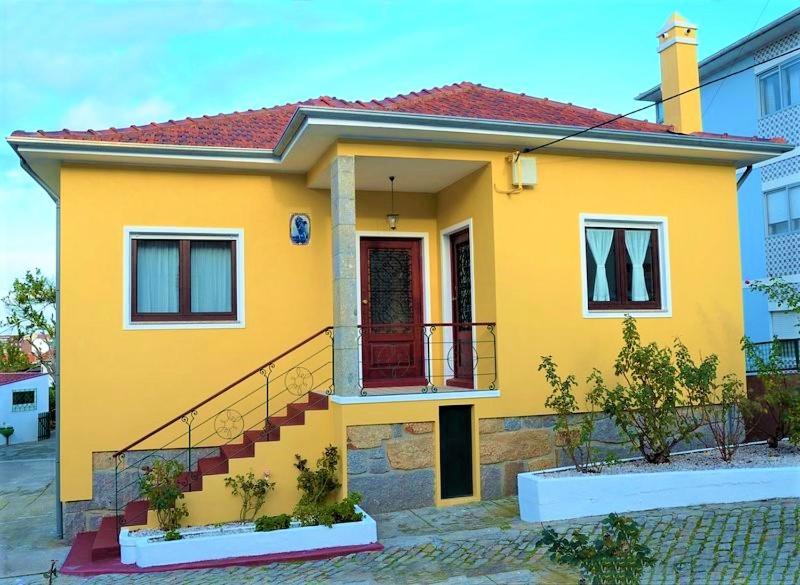 ein gelbes Haus mit einer roten Tür und einer Treppe in der Unterkunft Casa Celeste Portugal in Vila Nova de Gaia
