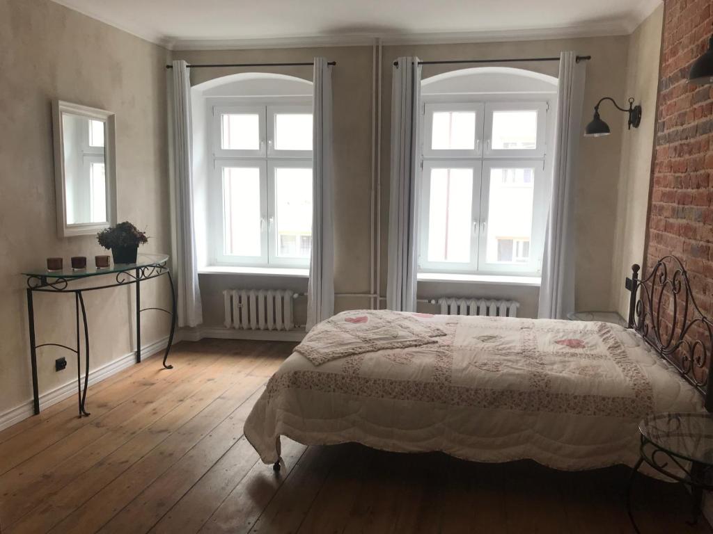a bedroom with a bed with two windows and a brick wall at Apartament Rustical in Wrocław