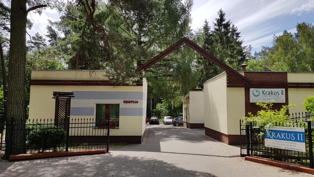 a building with a gate next to a parking lot at O.W. Krakus II - Domki i Pokoje in Stegna