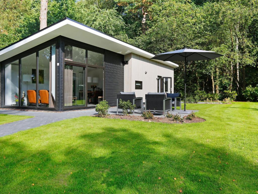 a small house with an umbrella in a yard at Chic Forest Lodge with Sauna in Markelo