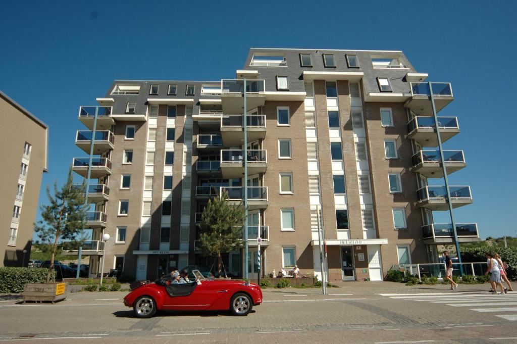 una macchina rossa parcheggiata di fronte a un edificio alto di Residence Deurloo 53-08 a Cadzand