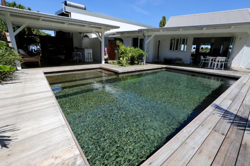 una piscina con terraza de madera y una casa en Kaza Blanka - Kaze Tropicale***** - Saint Leu - Réunion, en Saint-Leu