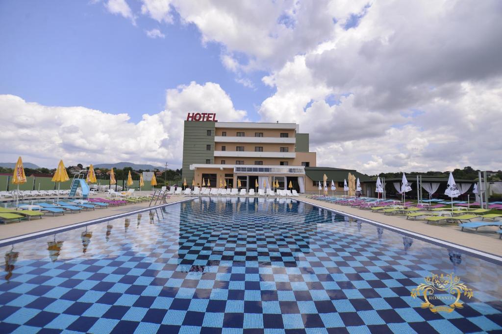 a hotel with a pool with chairs and a building at Hotel Romanita in Baia Mare