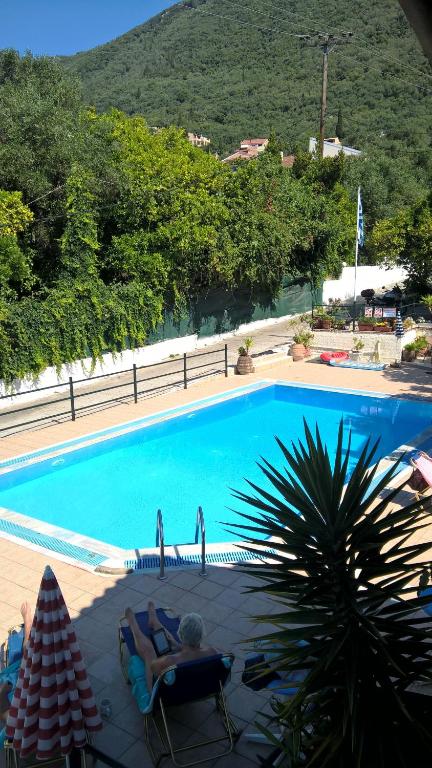 a woman laying in chairs by a swimming pool at ZOI & ALEXIA APARTMENTS in Ipsos