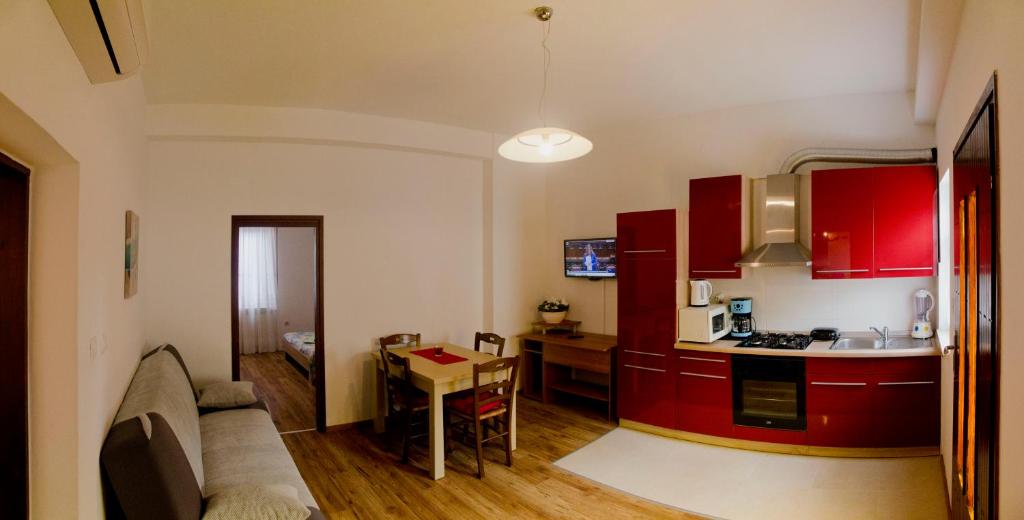 a kitchen with red cabinets and a table in a room at Apartman Aurora in Poreč