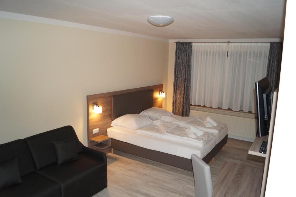 Habitación de hotel con cama y sofá en Hotel Tini, en Bad Fallingbostel
