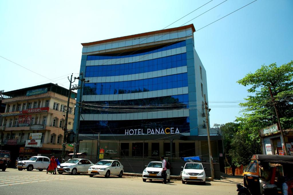 un gran edificio de cristal con coches estacionados frente a él en HOTEL PANACEA VENTURES, en Kollam