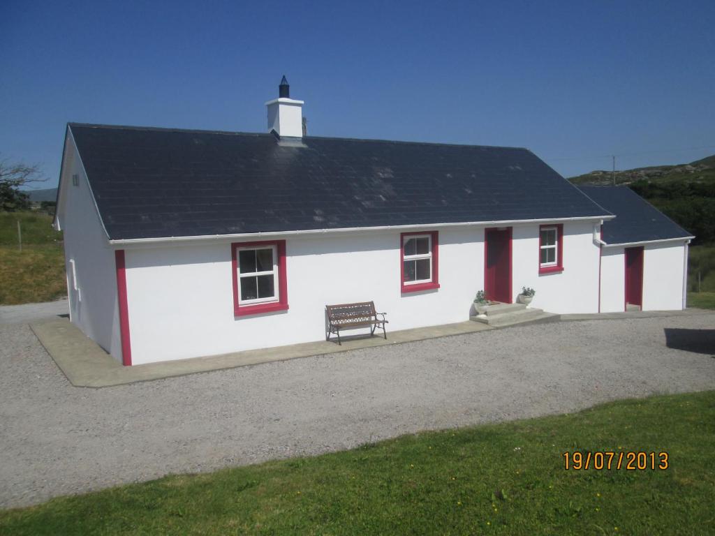 ein weißes Haus mit einer Bank davor in der Unterkunft Willies cottage in Donegal